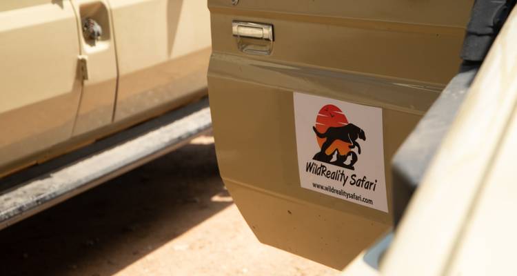 Gros plan sur la porte d'un véhicule de safari affichant un autocollant avec le logo de la compagnie WildReality Safari.