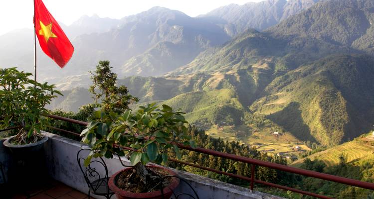 Balkon mit Bergblick in Sapa mit vietnamesischer Flagge über terrassierten Tälern bei Sonnenaufgang.