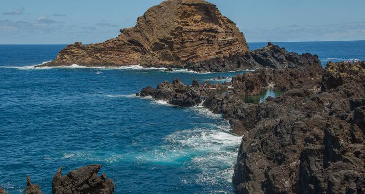 Côte volcanique rocheuse avec des vagues bleu profond de l'Atlantique s'écrasant contre des formations de basalte déchiquetées.