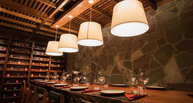Warm beleuchtetes rustikales Restaurantinterieur mit eingedecktem Esstisch und hängenden Lampen