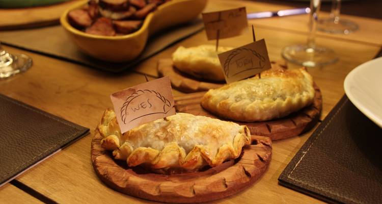 Frisch gebackene argentinische Empanadas mit handgeschriebenen Fähnchen beschriftet liegen auf Holztabletts bereit zum Servieren.