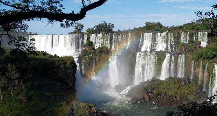Spektakulärer Blick auf die Iguazu-Wasserfälle mit einem leuchtenden Regenbogen, der sich durch den Nebel spannt.