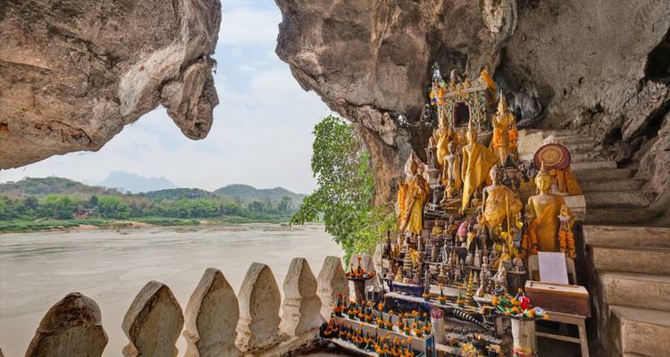 Heiligdom met gouden Boeddhabeelden in de Pak Ou-grot met uitzicht op de Mekong-rivier en kalkstenen heuvels.