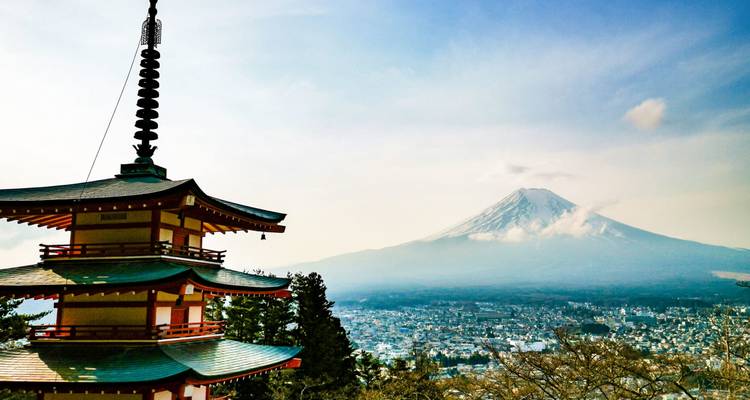 Iconische vijfverdieepse pagode die uitkijkt over een stad met de met sneeuw bedekte Mount Fuji die in de verte oprijst.