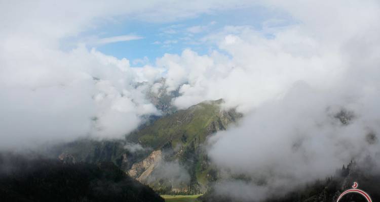 Dramatico paisaje montañoso parcialmente cubierto por nubes a la deriva y niebla desde un punto de vista elevado.