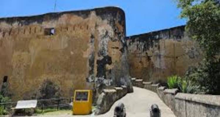 Fort Jesus stone walls with cannons at the entrance under a clear blue sky.