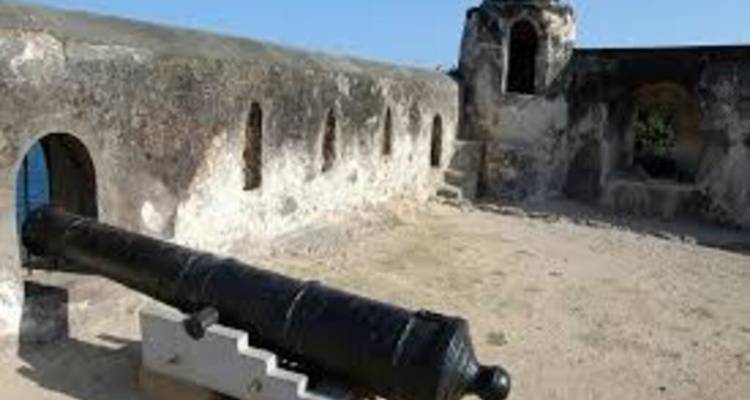 Weathered cannon pointing out from a stone bastion overlooking the sea.