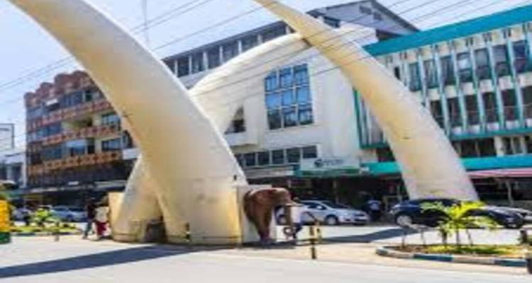 Iconic white tusk arches straddling Moi Avenue with traffic and buildings in Mombasa.