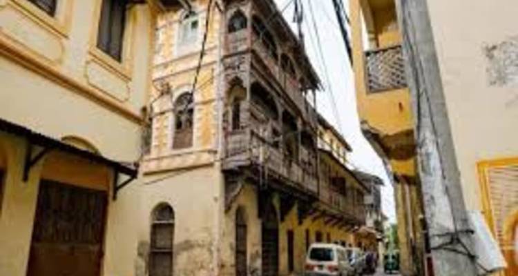 Narrow alley in Mombasa Old Town lined with ornate wooden balconies and weathered facades.