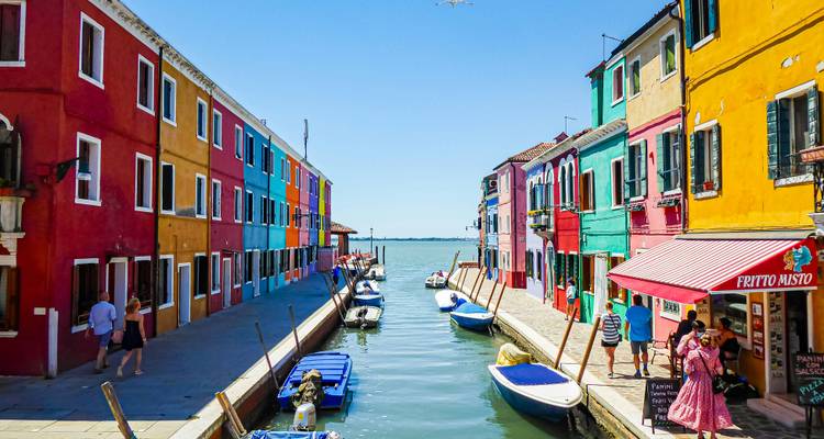 Des maisons aux couleurs vives bordent un canal étroit rempli de petits bateaux dans le village insulaire coloré de Burano.