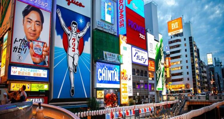 Levendige neonreclames en avondmenigten langs de Dotonbori kanaalwijk in Osaka.