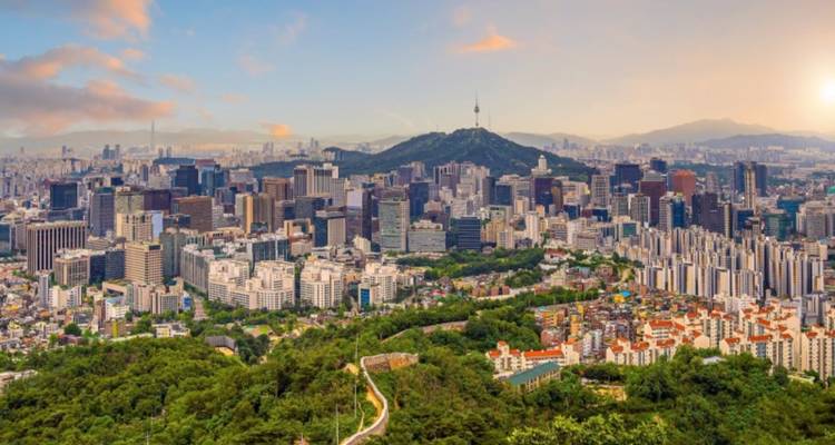 Panoramisch uitzicht op de skyline van Seoel met de Namsan Seoul Tower die boven de dicht opeengepakte wolkenkrabbers uit torent bij zonsondergang.