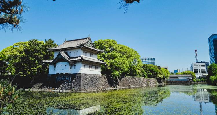 Wachturm des Kaiserlichen Palastes von Tokio, gespiegelt in einem ruhigen Burggraben an einem strahlend blauen Tag
