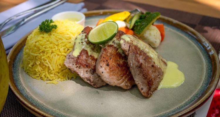 Steak de thon grillé avec riz jaune, légumes et sauce crémeuse présenté pour le déjeuner