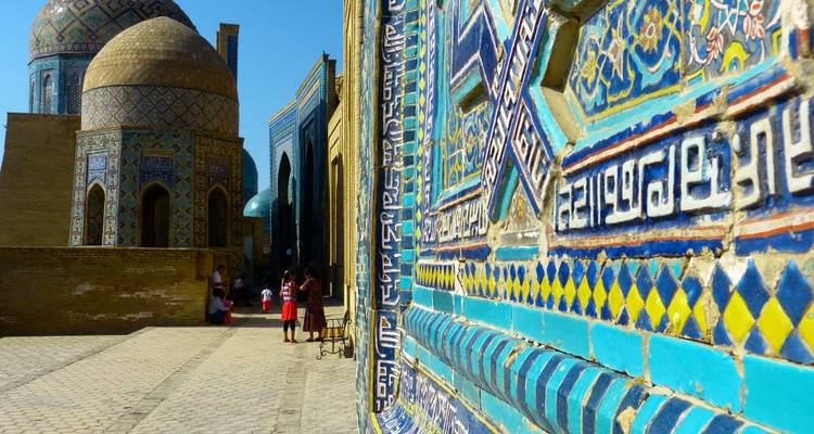 Tumbas de mosaico azul intrincado de Shah-i-Zinda en Samarcanda con visitantes explorando el callejón estrecho