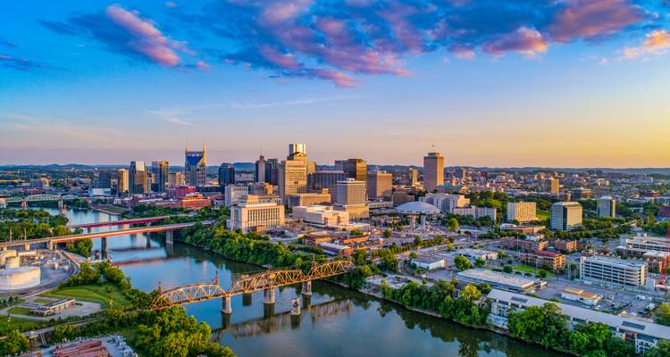 Vue aérienne d'un coucher de soleil vibrant sur l'horizon de Nashville avec des ponts enjambant la rivière Cumberland.