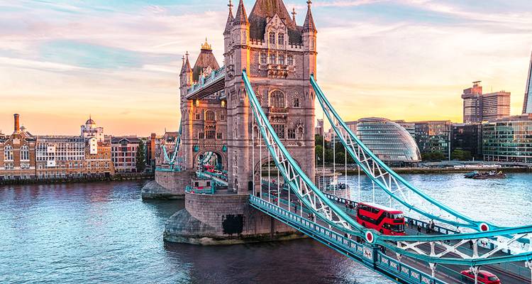Vista aérea al atardecer del Tower Bridge de Londres con un autobús rojo de dos pisos cruzando el Támesis.