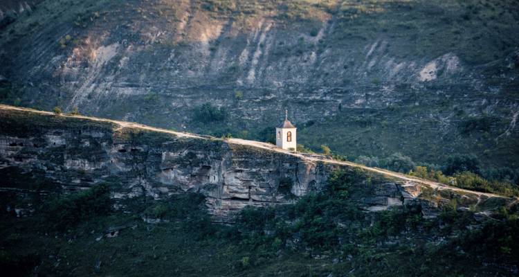 Pequeña capilla solitaria en lo alto de un dramático acantilado bañada por la luz del atardecer.