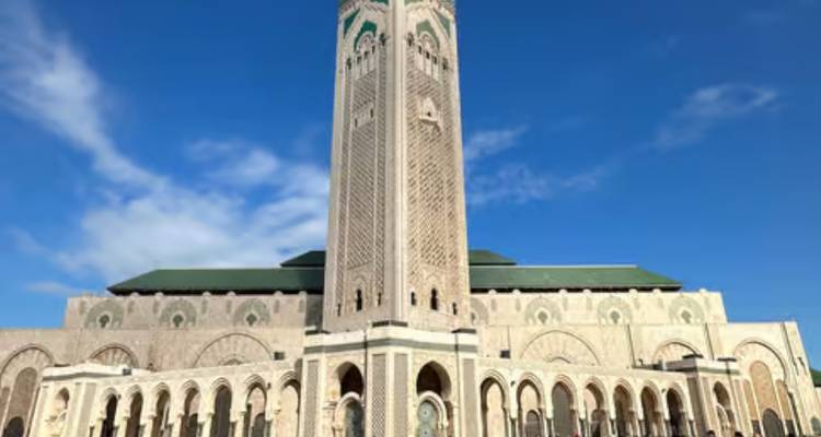 Vue de face du minaret de la Mosquée Hassan II s'élevant dans un ciel bleu dégagé.