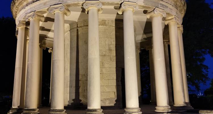 Monument circulaire illuminé avec de hautes colonnes en marbre, photographié à l'heure bleue.