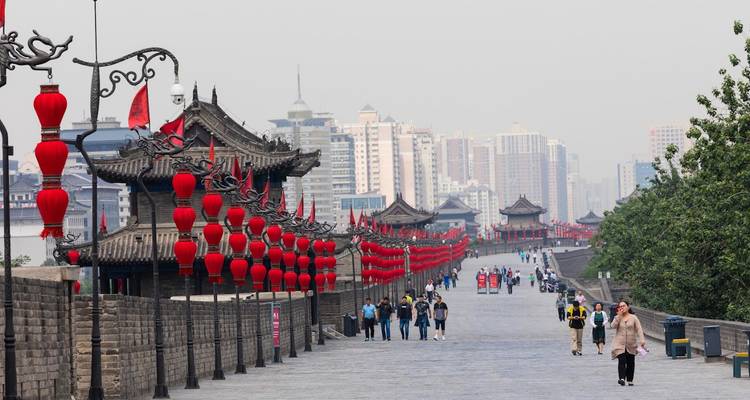 Fußgänger auf der Xi'an-Stadtmauer-Promenade, gesäumt von roten Laternen und alten Dächern.