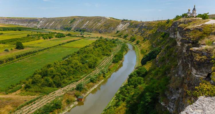 Panoramisch uitzicht op de Răut-rivier die zich slingert onder hoge kalksteenrotsen bij een klooster op een heuveltop in Moldavië.