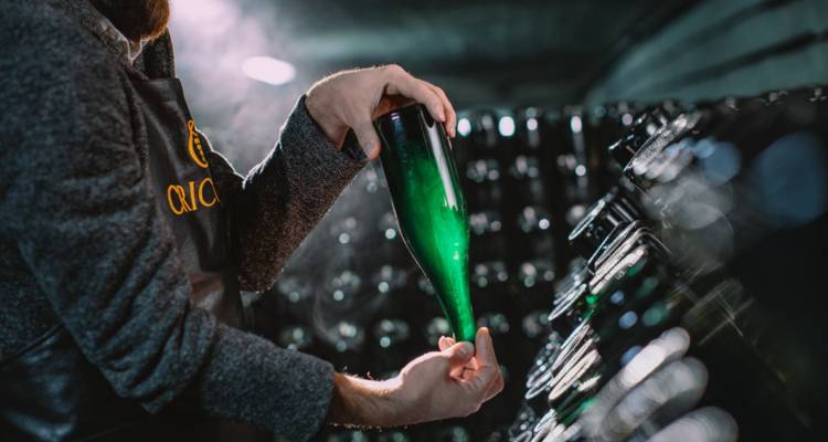 Wijnmaker die een fles spumante inspecteert in de donker verlichte ondergrondse kelders van Cricova.