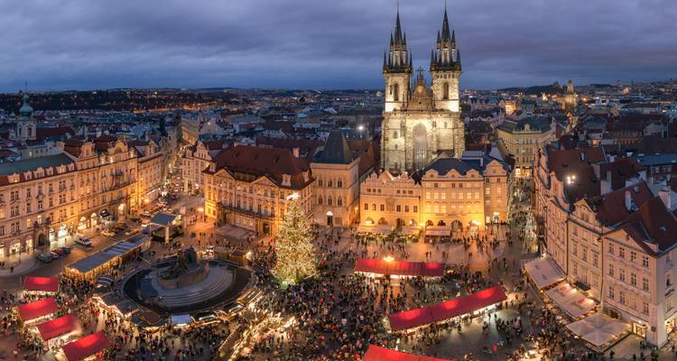 Luftaufnahme am Abend des Altstädter Rings in Prag mit festlichen Marktständen und den Zwillingstürmen der Teynkirche.