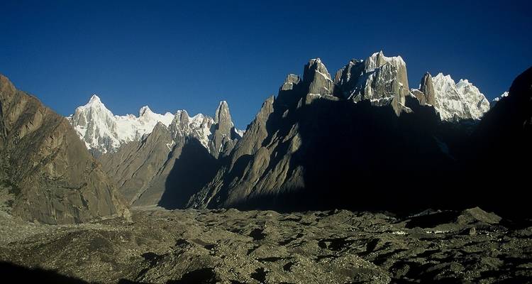 Dramatic jagged peaks of Karakoram range rising above rocky glacier valley.