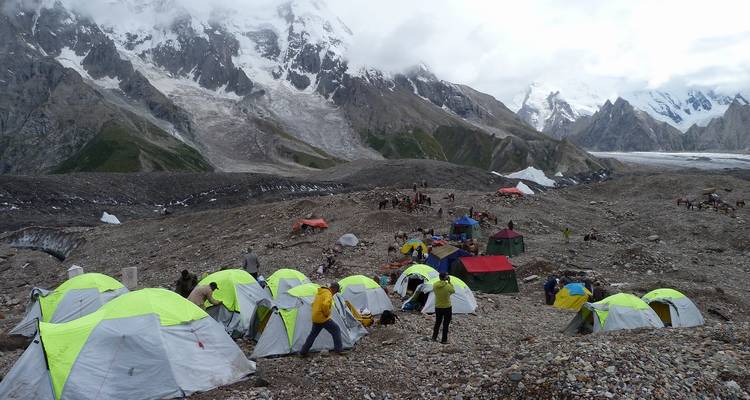 Expedition basecamp with neon tents scattered across rocky glacier landscape.