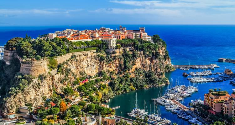 Vue aérienne de la vieille ville perchée sur les falaises de Monaco et de sa marina entourées par la mer bleu profond.