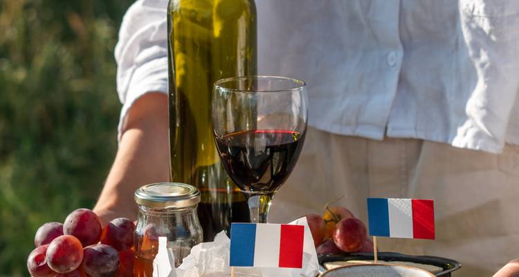 Detail of French picnic setup with wine glass, grapes and flag on cheese