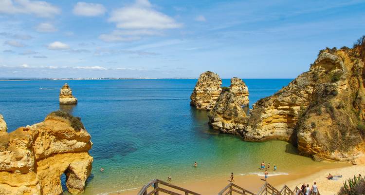Türkisfarbene Bucht mit goldenen Felsformationen und Badegästen an der Ponta da Piedade in der Nähe von Lagos.