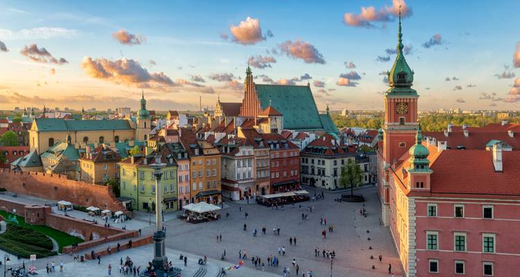 Panorámica aérea de la Plaza de la Ciudad Vieja de Varsovia en la hora dorada con fachadas coloridas y el Castillo Real.