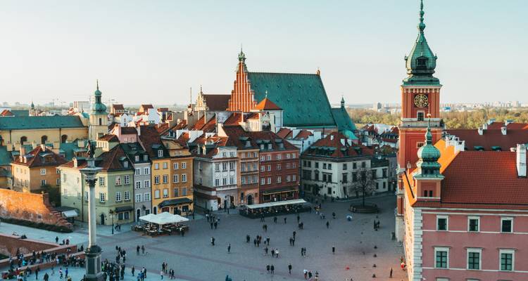 Vista aérea diurna de la plaza de la Ciudad Vieja de Varsovia con edificios en tonos pastel y aguja de iglesia.