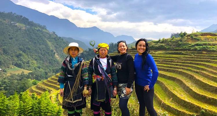 Reisende und einheimische Hmong-Frauen, die sich mit terrassierten Reisfeldern und nebligen Bergen im Hintergrund fotografieren lassen.