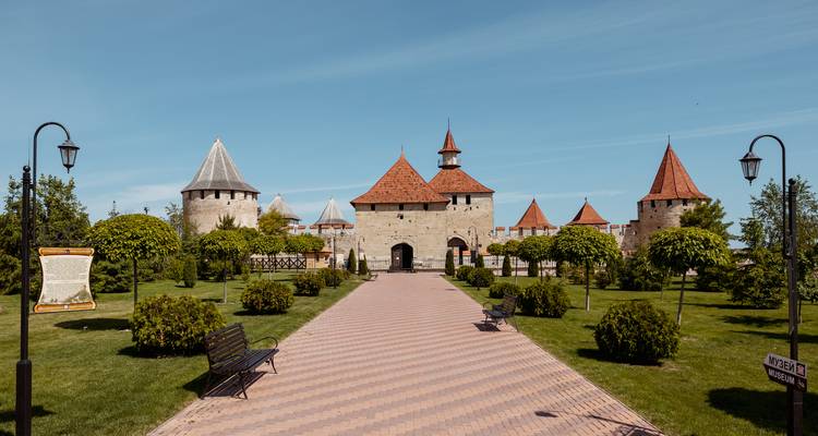 Recht voetpad dat leidt naar de rode daken van de torens en de stenen poort van Bender Fortress op een heldere dag.
