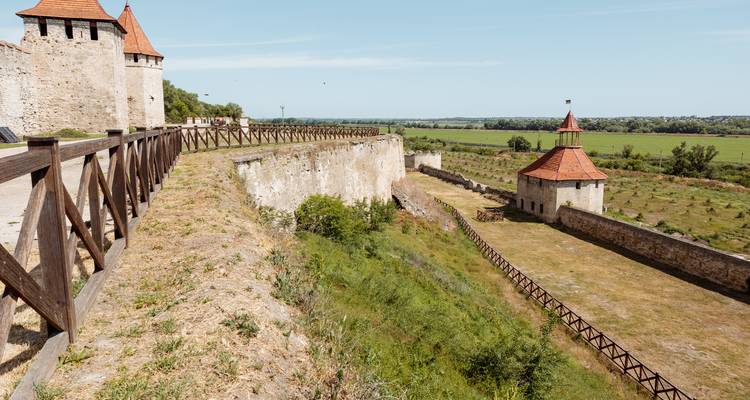Versterkte stenen muren en een wachttoren met uitzicht op het groene Moldavische platteland.