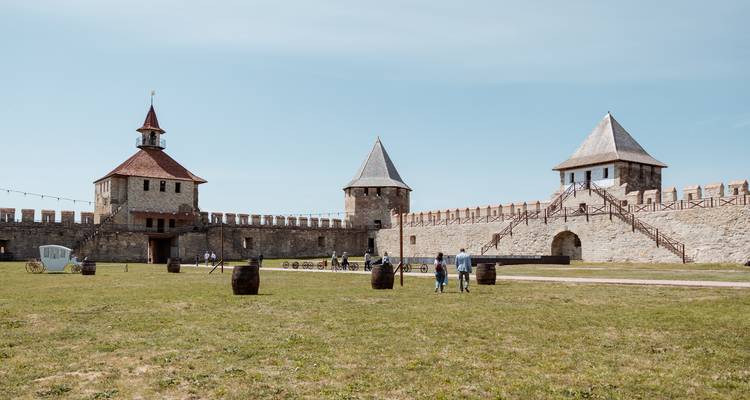 Open grassy courtyard within Bender Fortress with scattered visitors and timber barrels.