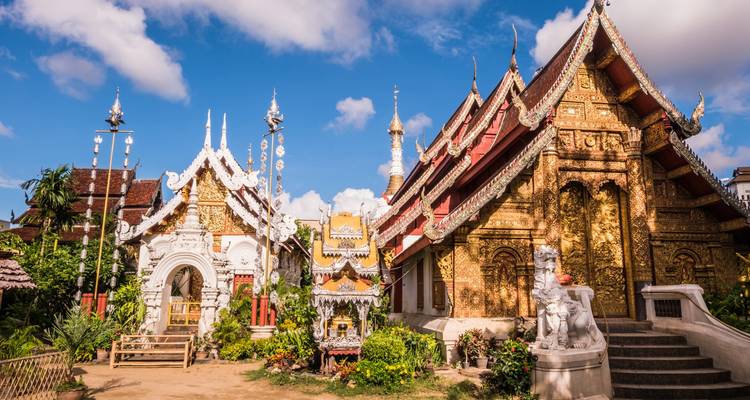 Des temples bouddhistes dorés richement décorés avec des toits ornementés sous un ciel bleu éclatant