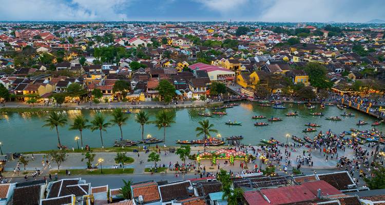 Atardecer aéreo del Pueblo Antiguo de Hoi An con el río lleno de vida, botes iluminados con faroles y calles bulliciosas.