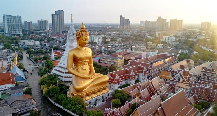 Vue aérienne de la skyline urbaine de Bangkok avec un immense Bouddha doré assis dominant la ville.