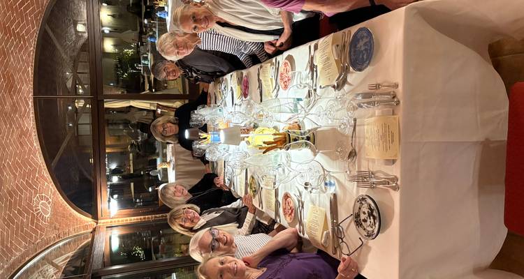 Huit amis assis autour d'une table de diner élégamment dressée dans un restaurant aux voutes architecturales.