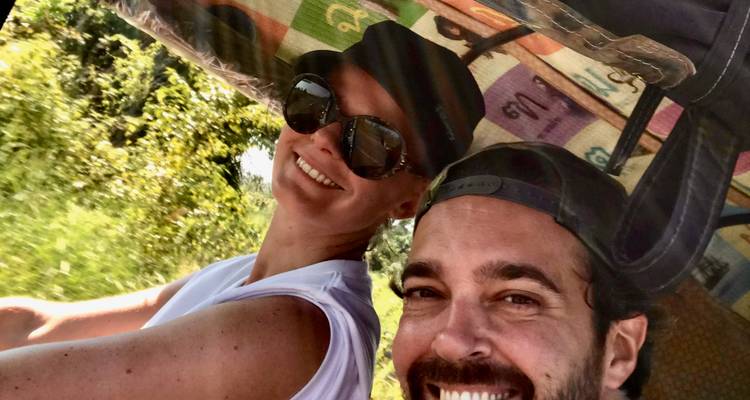 Gelukkig stel dat een selfie maakt in een kleurrijke tuk-tuk met een gemusterd dak op een zonnige dag.