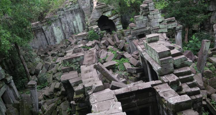 Eingefallene, von Dschungel bewachsene Steinblöcke und Türöffnung einer antiken Khmer-Tempelruine.