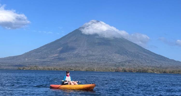 Kajaker voor de met wolken bedekte Concepción Vulkaan die boven het blauwe water van het Nicaraguameer uittorent.
