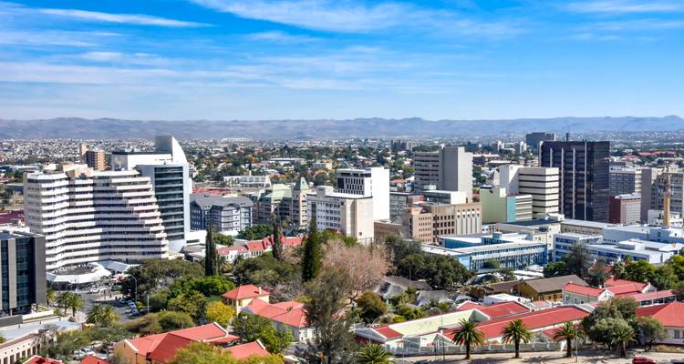 Panoramisch stadssilhouet van Windhoek met moderne wolkenkrabbers en bergen in de verte onder helder weer.