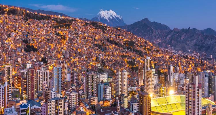 Les lumières du soir enveloppent les collines de La Paz avec l'Illimani aux sommets enneigés se dressant au loin.