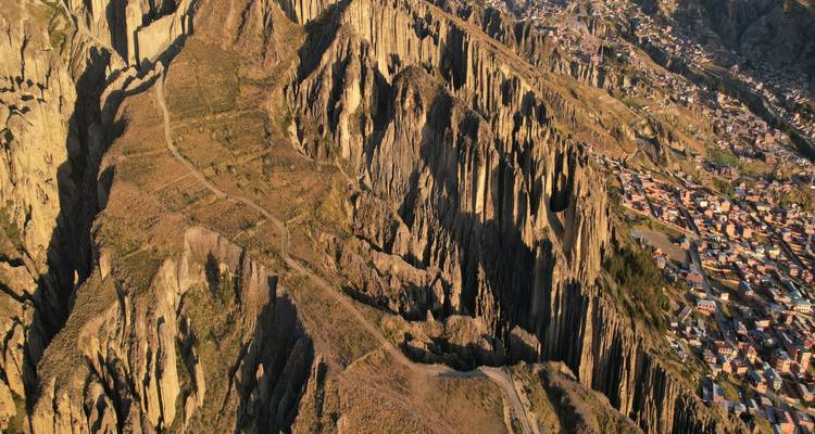 Les falaises spectaculairement érodées et les pics rocheux dominent un paysage accidenté avec une agglomération urbaine nichée au-delà.