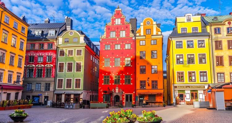 Las fachadas vibrantes de la plaza Stortorget en el Gamla Stan de Estocolmo bajo un cielo azul vívido.